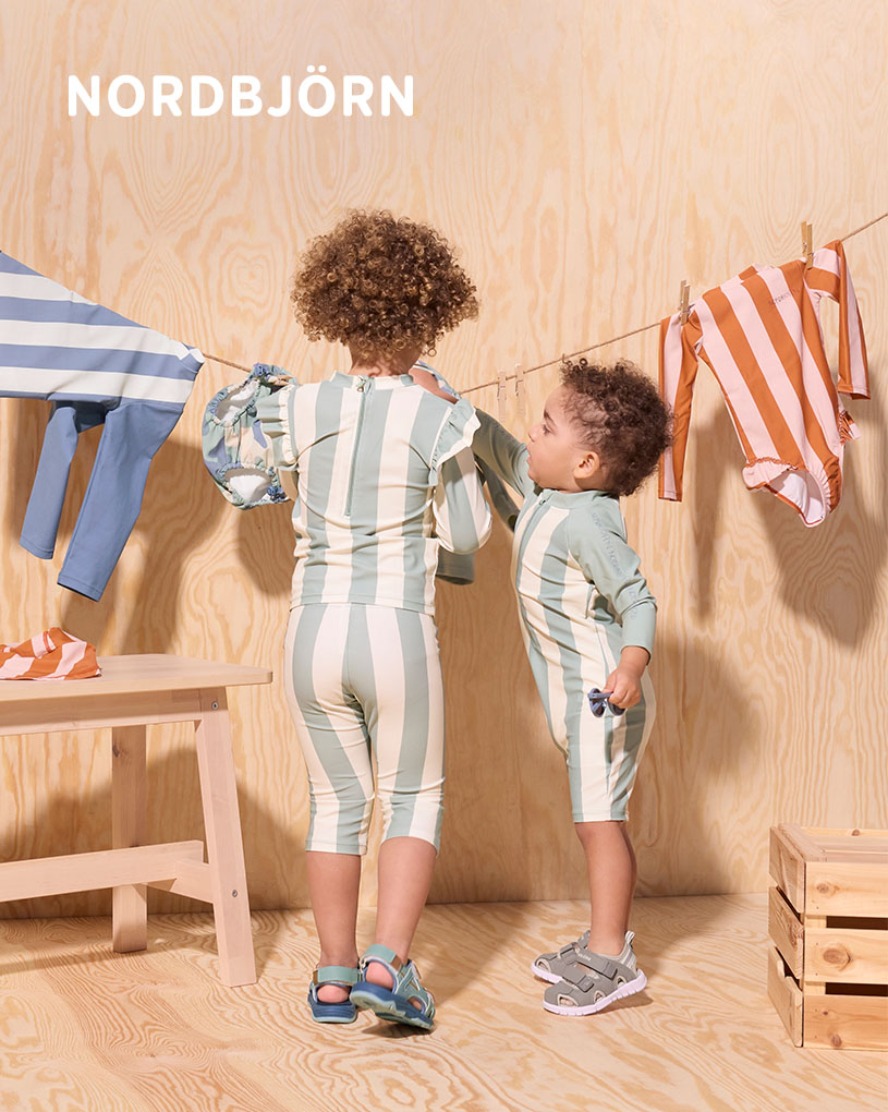 Barn i solhat leger med spande på en træterrasse.